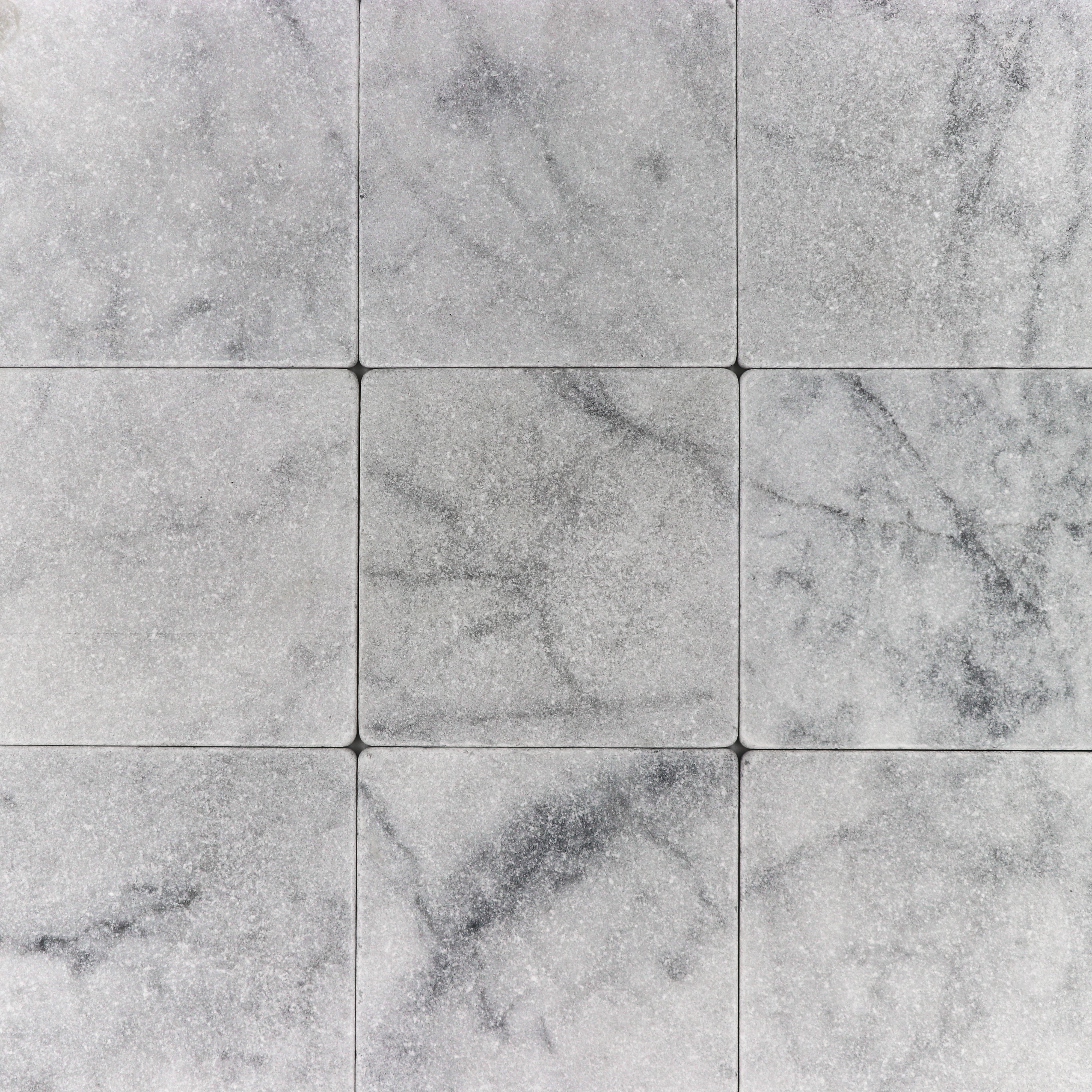 Tumbled Carrara White marble tile, 6x6, with natural gray patterns.